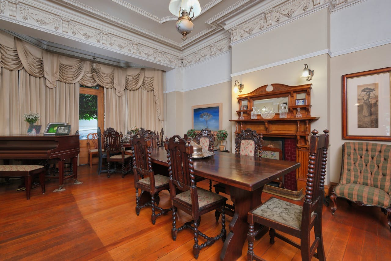 Victorian-style dining room with ornate furniture, fireplace, and grand piano.